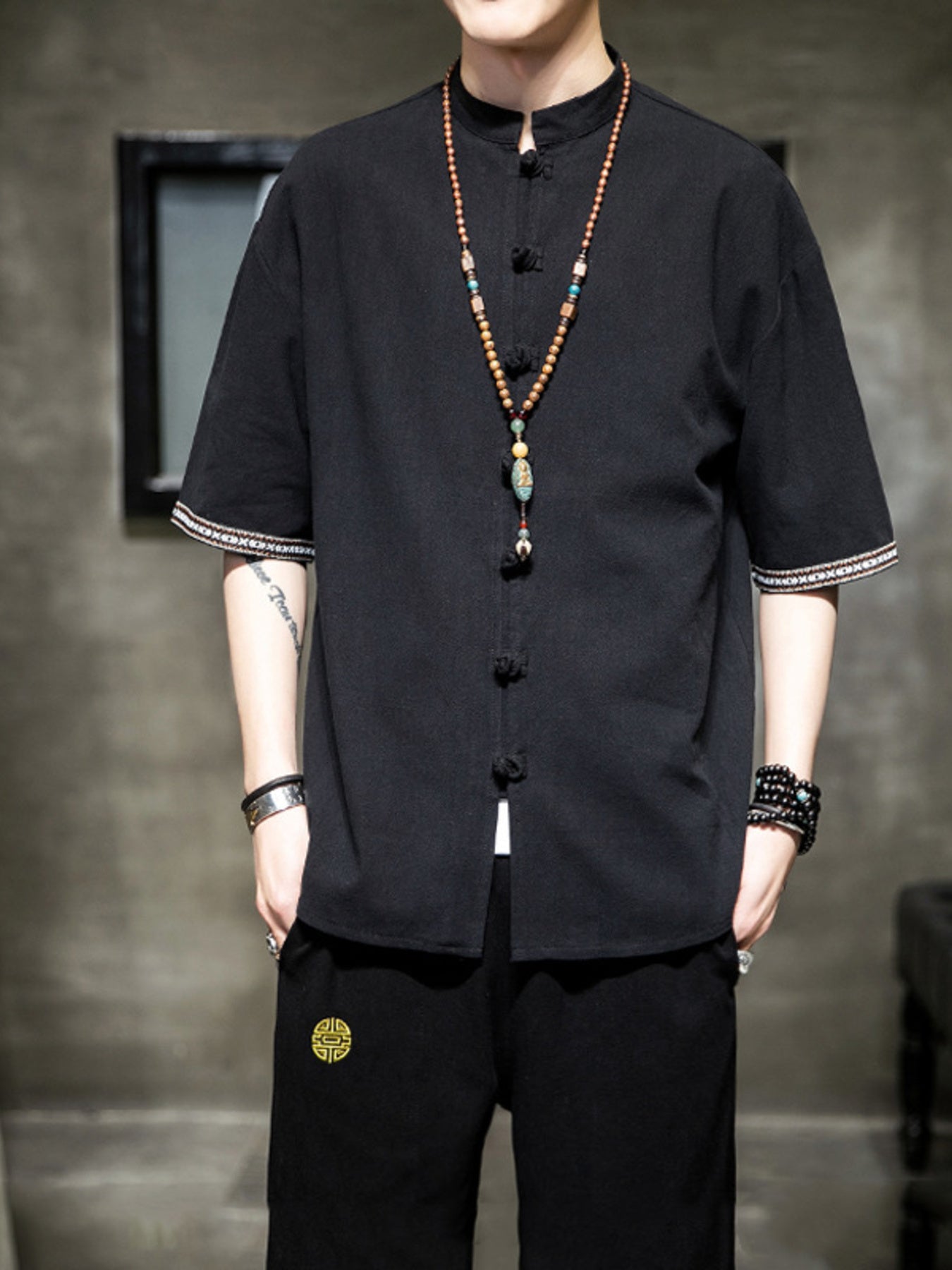 Black cotton blend short sleeve shirt with mandarin collar and decorative buttons.