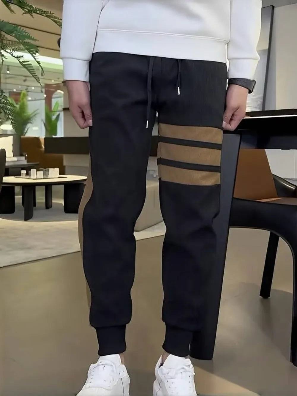 Men's black sweatpants with caramel stripe detail and drawstring waist.