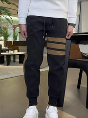 Men's black sweatpants with caramel stripe detail and drawstring waist.