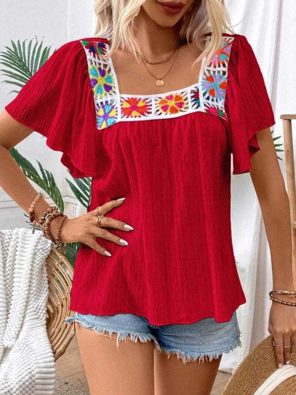 Red embroidered square neck flutter blouse with colorful floral detail on neckline.