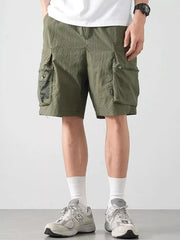 Green cargo shorts with multiple zippered and mesh pockets.