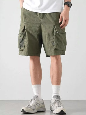 Green cargo shorts with multiple zippered and mesh pockets.