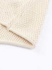 Beige knit sweater with textured stitch detail and ribbed hem.