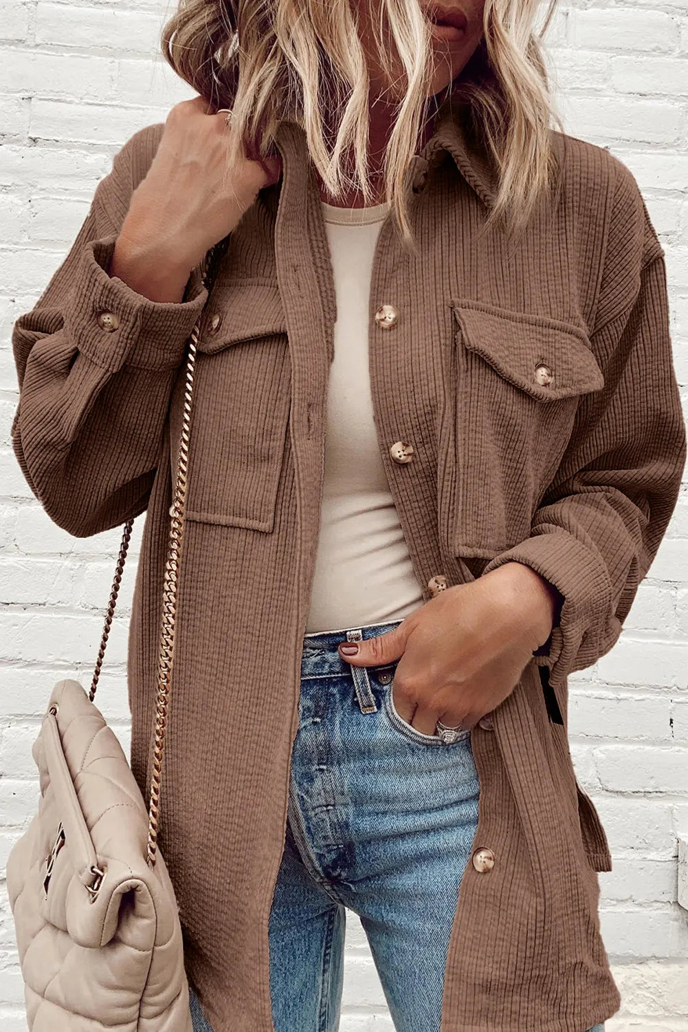 Brown corduroy oversized utility jacket with button-flap chest pockets and button cuffs.