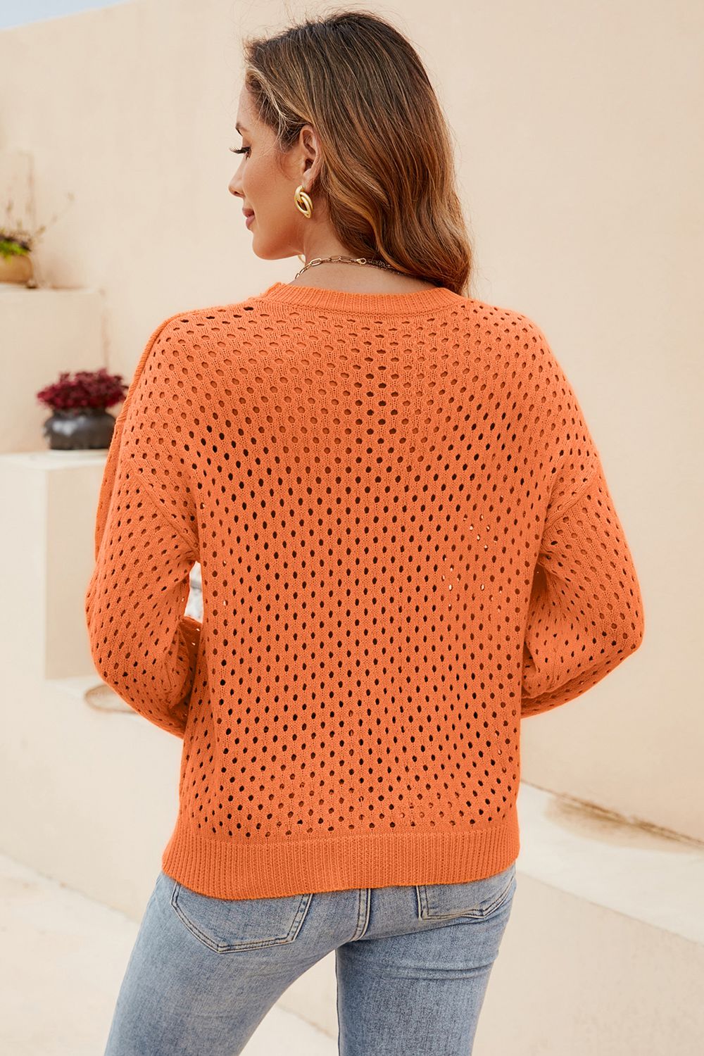 Orange open-knit crewneck sweater with subtle texture and long sleeves.