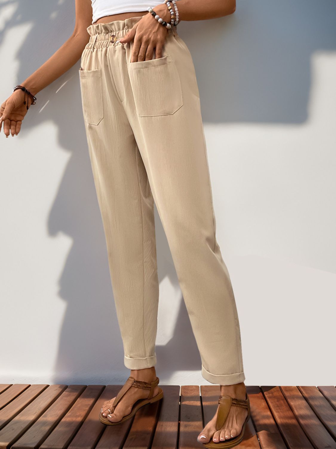 Tan linen blend trousers with gathered waist, pockets, and cuffed hem.
