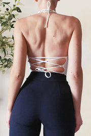 White halter crop top with lace-up back detail and tie closure.