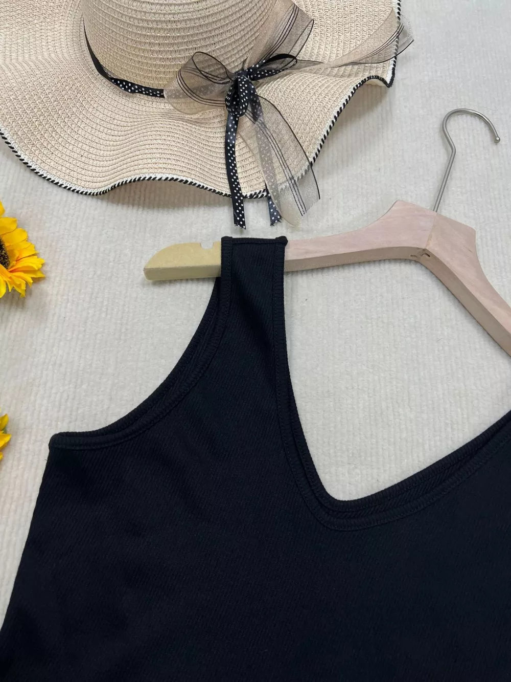Black ribbed V-neck tank top with a close-up view of the neckline and shoulder strap.