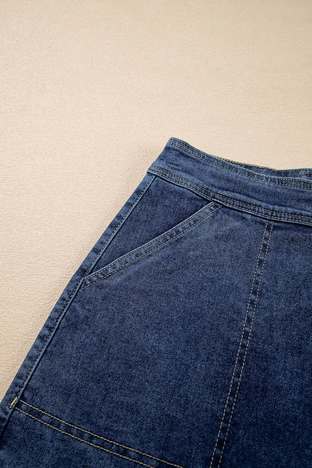 Denim wrap skort in medium blue with asymmetrical patch pockets and contrast stitching.