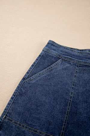 Denim wrap skort in medium blue with asymmetrical patch pockets and contrast stitching.