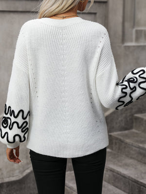 White knit sweater with voluminous sleeves featuring black abstract embroidery.