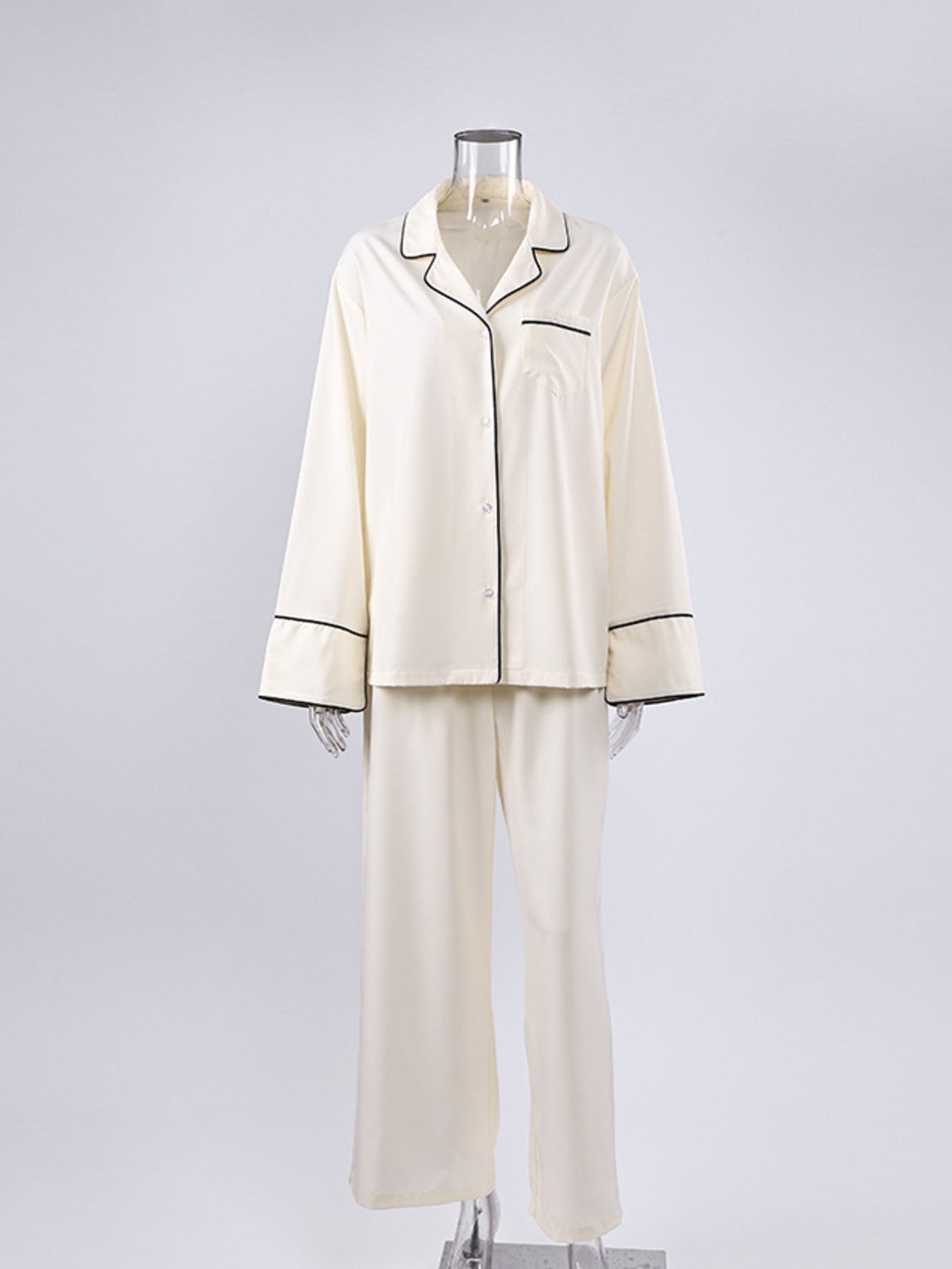 Button-up pajama set in cream with black piping, long sleeves, and matching pants.