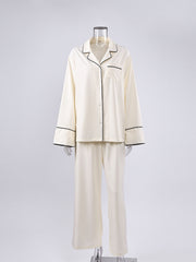 Button-up pajama set in cream with black piping, long sleeves, and matching pants.