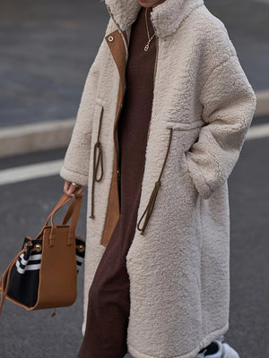 Oversized beige sherpa coat with suede accents and drawstring details.