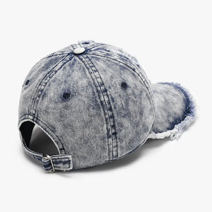 Acid wash frayed denim baseball cap in dark blue with distressed details and adjustable strap.