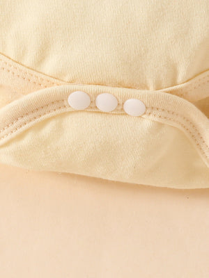 Yellow baby bodysuit detail with three white snaps