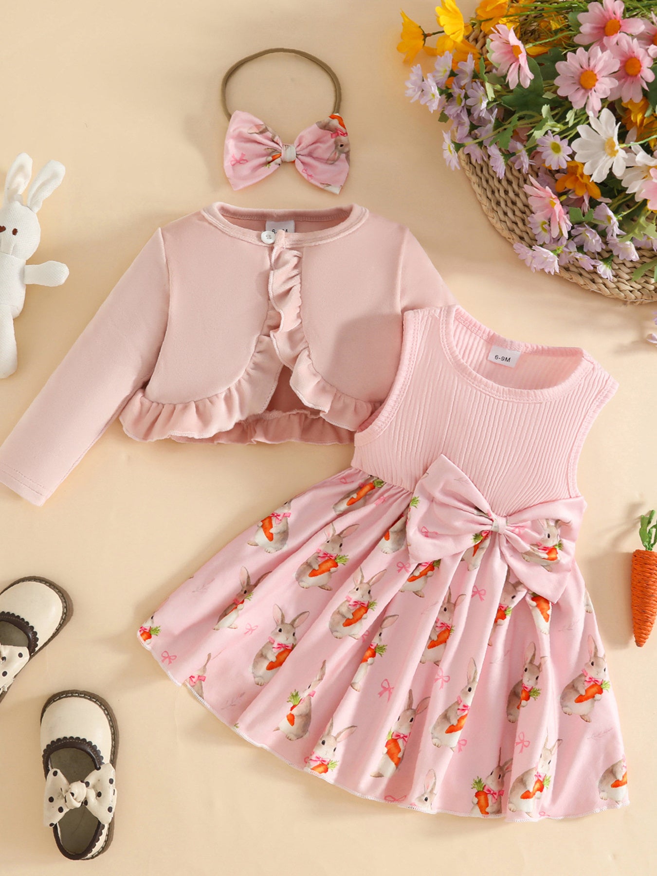 Pink baby dress with bunny and carrot print, ruffled cardigan, and bow headband.