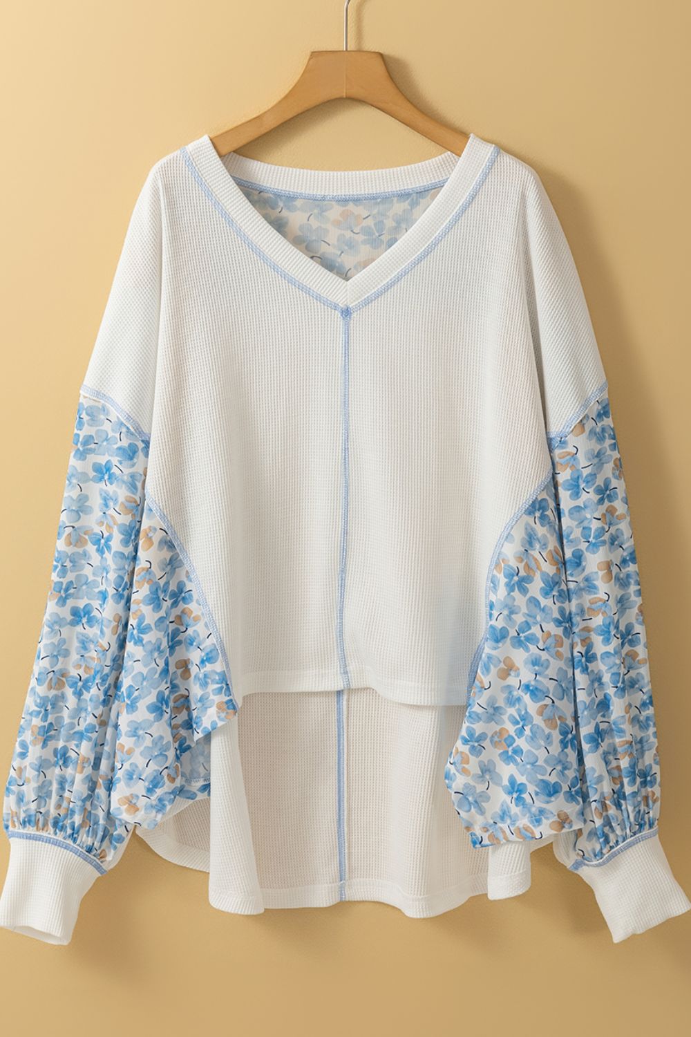 Waffle knit blouse in white with blue floral print sleeves and V-neck.