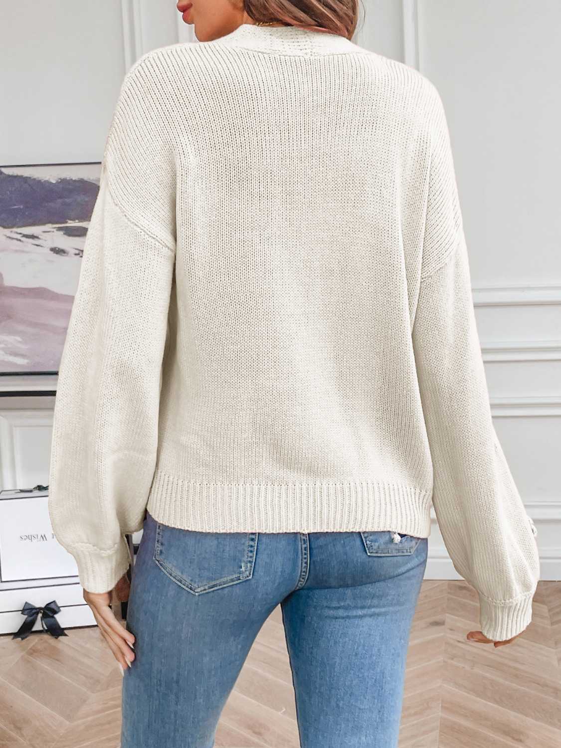 White acrylic knit cardigan with embroidered blossoms on sleeves, relaxed fit, ribbed cuffs and hem.