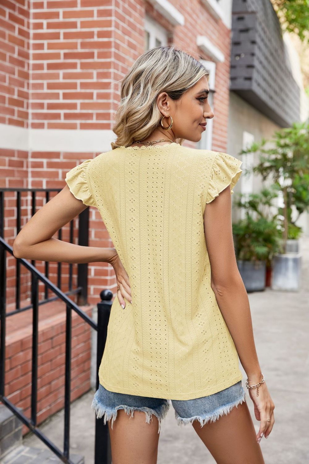 Yellow eyelet blouse with lace trim flutter sleeves and a scalloped neckline.