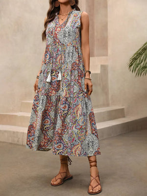 Paisley print midi dress with tie neck, decorative tassels, and tiered skirt.