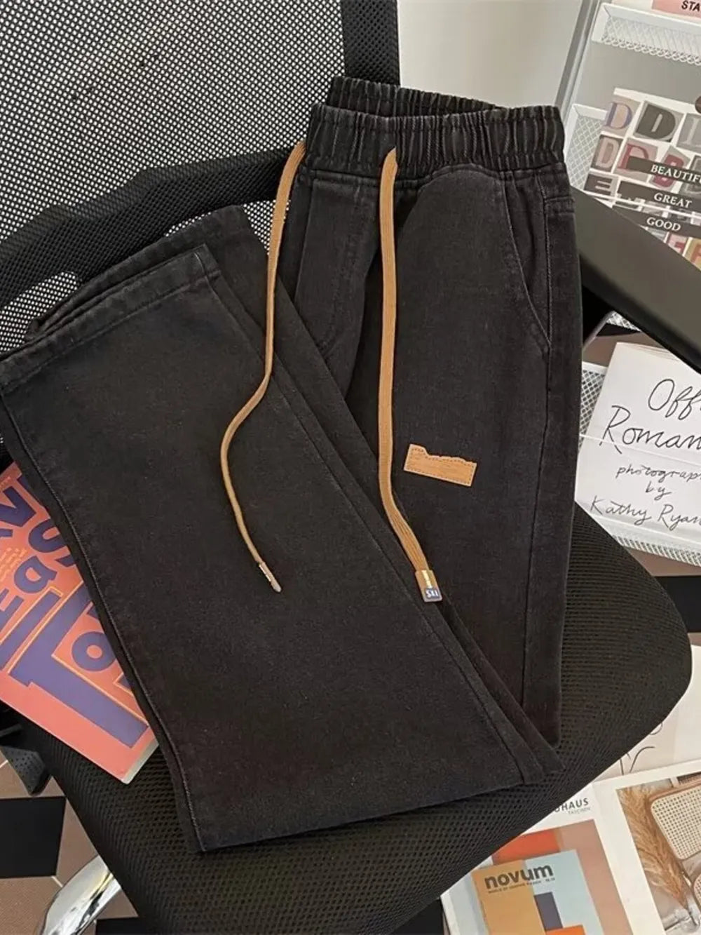 Black wide-leg jeans with drawstring waist and tan drawstring.