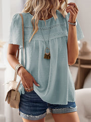 Light blue textured puff sleeve blouse with crochet yoke detail and tassel necklace.