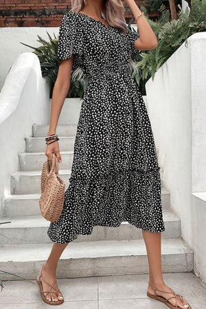 Black floral midi dress with smocked waist, flutter sleeves, and tiered skirt.