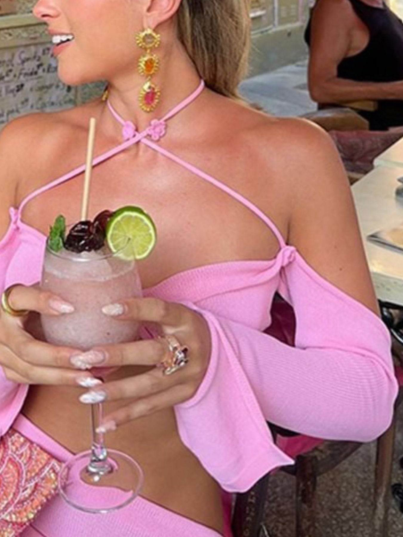 Pink halter neck knit set with flower detail and long sleeves, styled with jewelry.