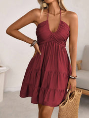 Burgundy ruched halter tiered mini dress with ruffles and a deep V-neckline.