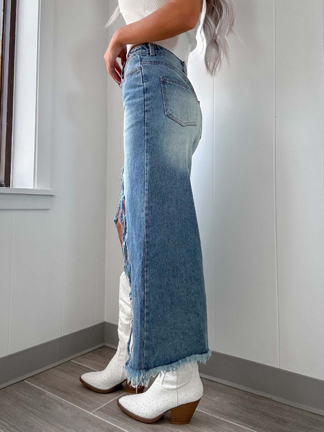 Distressed denim maxi skirt in light wash with a side slit and frayed hem.