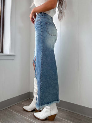 Distressed denim maxi skirt in light wash with a side slit and frayed hem.