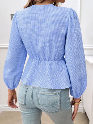 Dusty blue textured peplum blouse with cinched waist and puff sleeves.