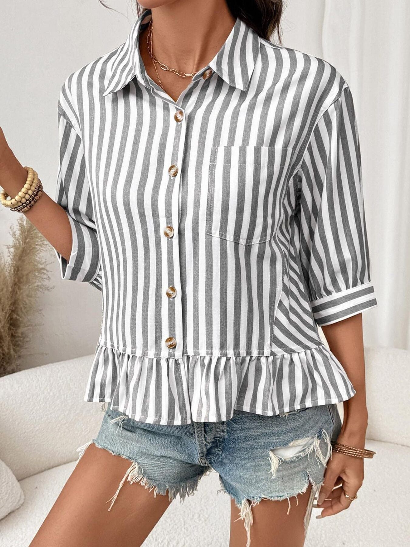 Button-down shirt with ruffle hem and 3/4 sleeves in gray and white stripes.