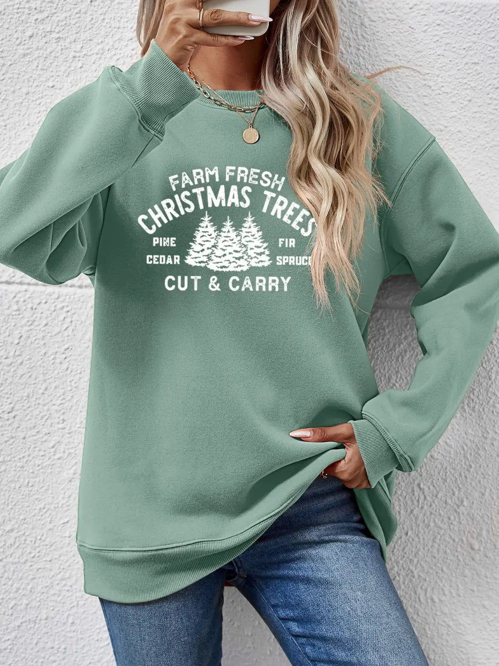 Sage green crewneck sweatshirt with white Christmas tree graphic and text.