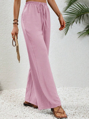 Pink textured palazzo trousers with drawstring waist and wide legs.