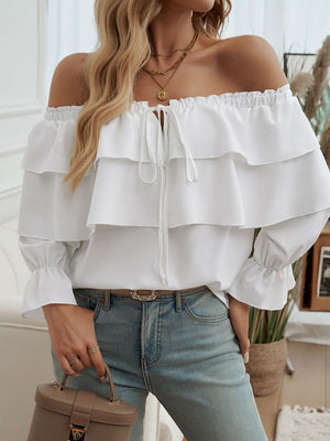 White tiered ruffle off-shoulder blouse with tie neck and ruffled cuffs.