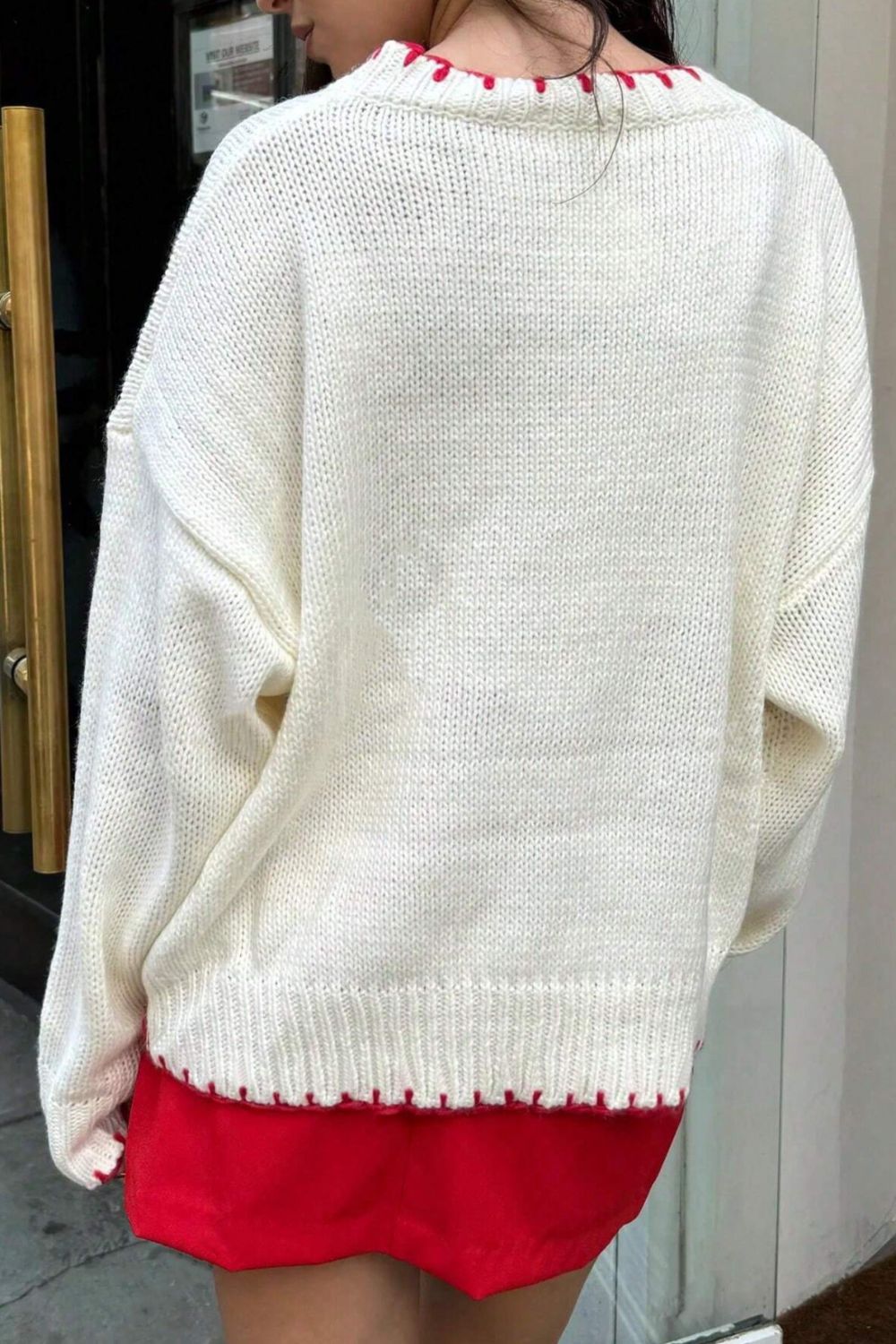 White knit crewneck sweater with red stitching detail at neckline and hem