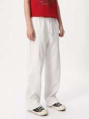 Cream cotton drawstring sweatpants with wide legs and a tailored fit.