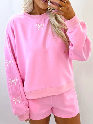 Pink loungewear set with embroidered bows on sweatshirt sleeves and chest