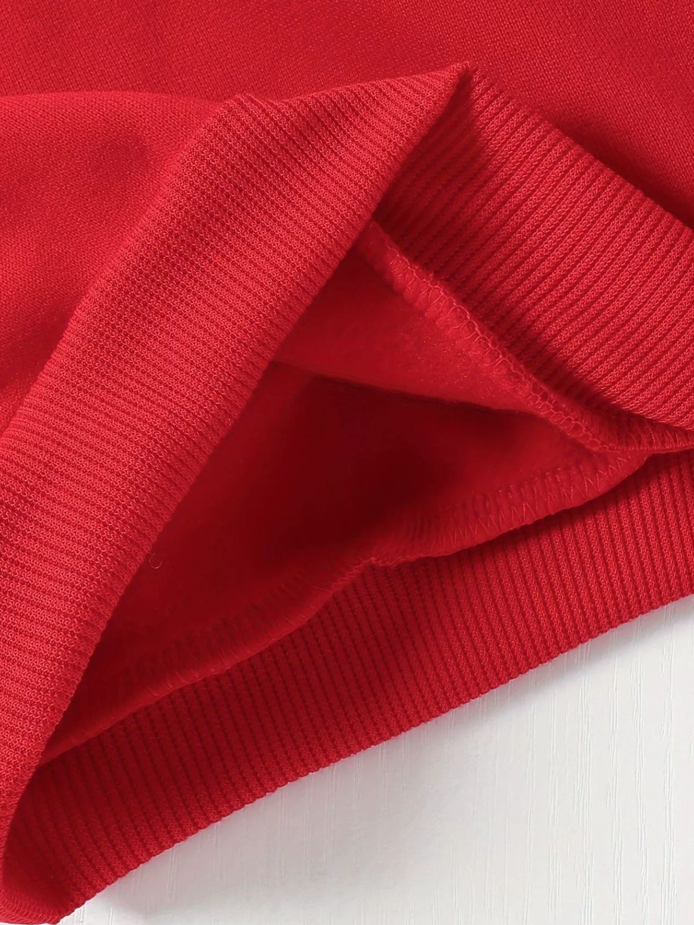 Red baby hoodie detail showing ribbed cuffs and soft fleece lining.
