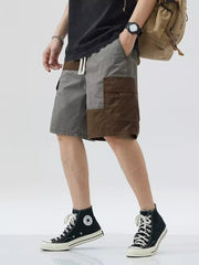 Two-tone cargo shorts with drawstring, above-knee length, featuring brown and grey color block panels and cargo pockets.