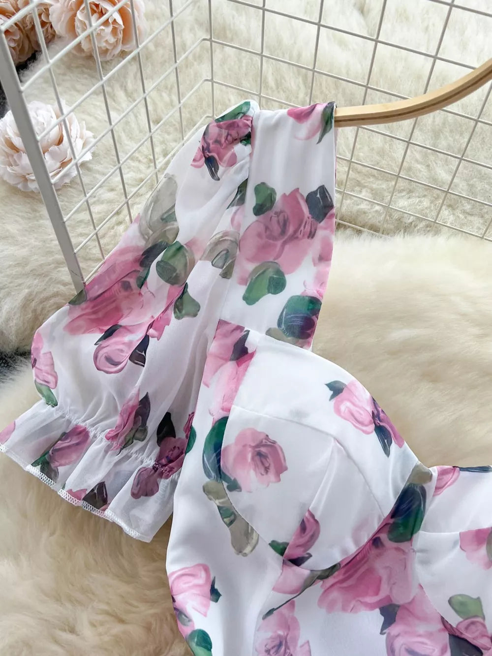 White floral midi dress with pink roses, puff sleeves, and ruffle hem detail.