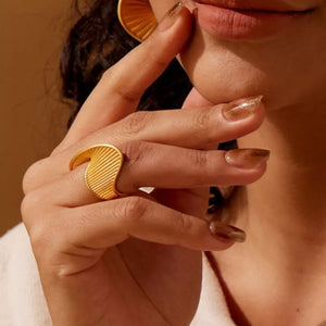 18k gold-plated ring with twisted texture and ribbed detail on a woman's hand.
