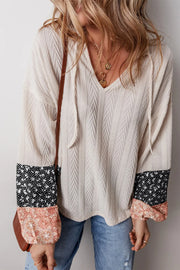Textured sleeve henley blouse with patchwork floral cuffs and tie-neck detail.