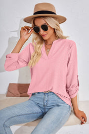 Pink textured henley blouse with rolled sleeves and V-neck.