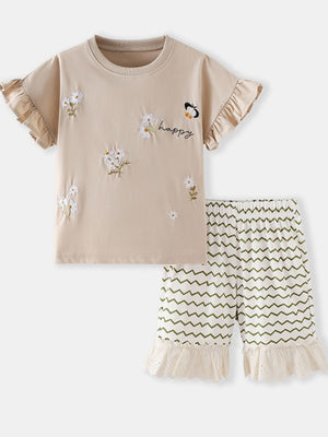 Beige cotton tee with embroidered flowers, butterfly, and "happy" text, paired with white shorts with green zigzags and