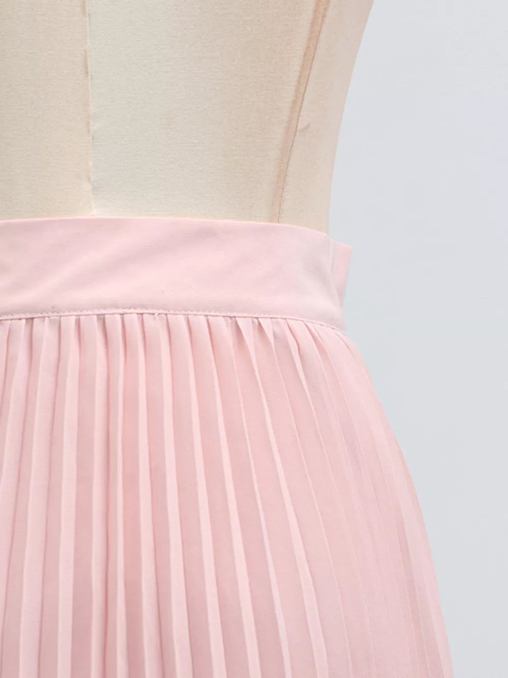 Pink pleated skirt with a wide waistband, part of a two-piece ensemble.