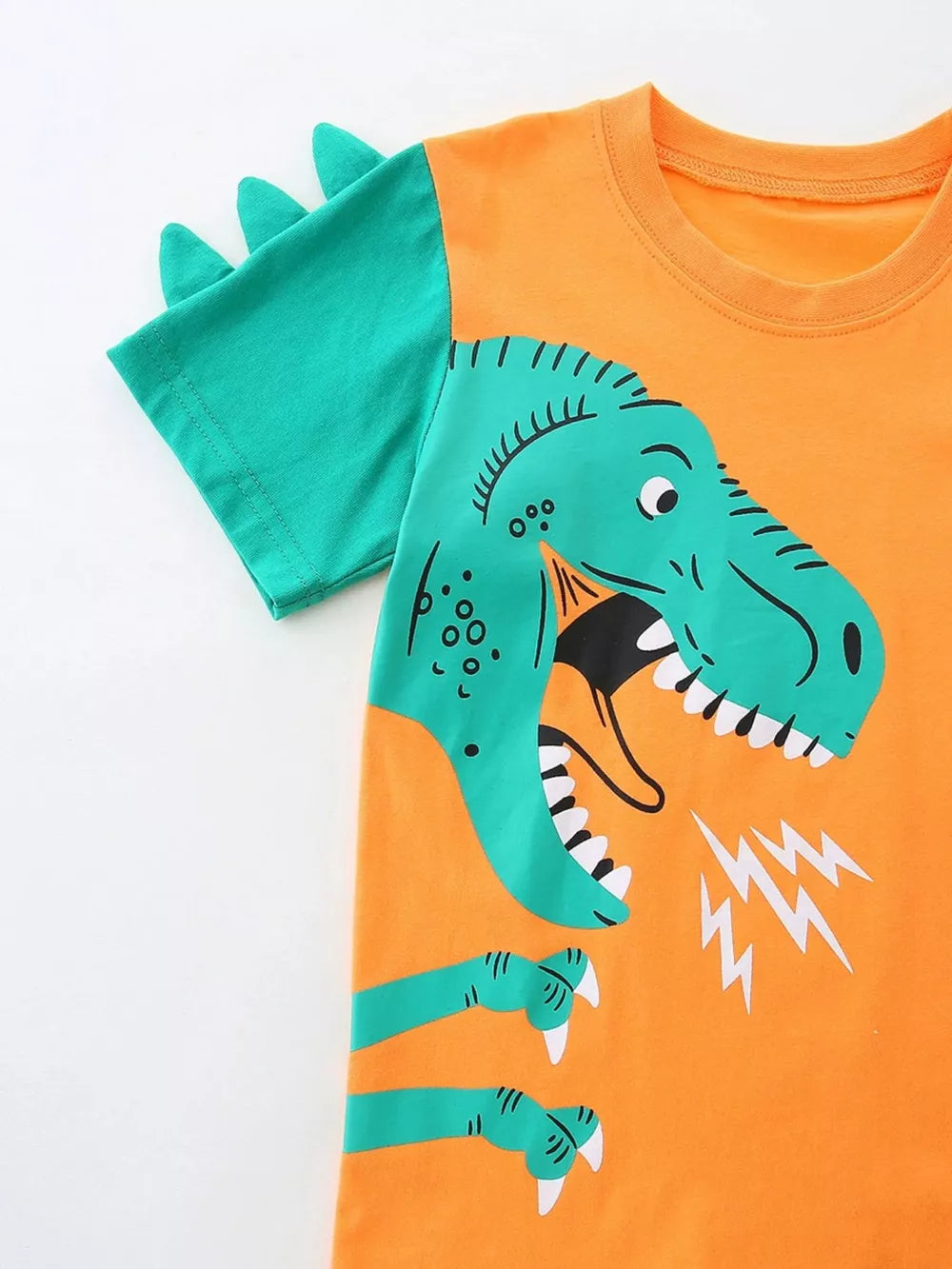 Orange cotton tee with green dinosaur graphic and spike details on sleeves.