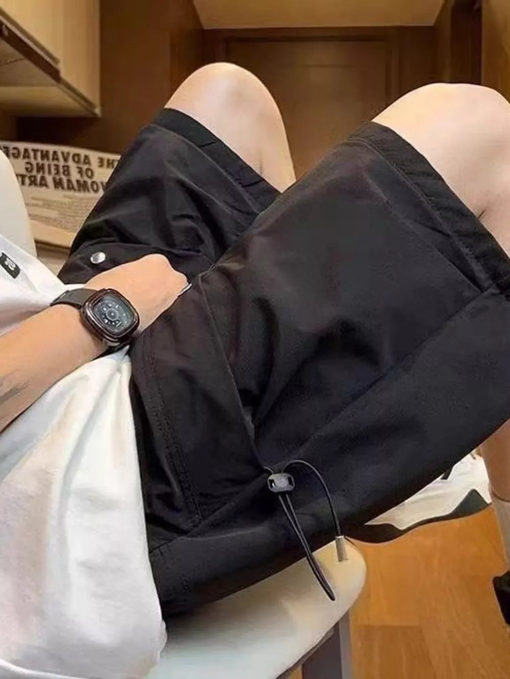 Black lightweight cargo shorts with drawstring detail and pockets, worn by a man.